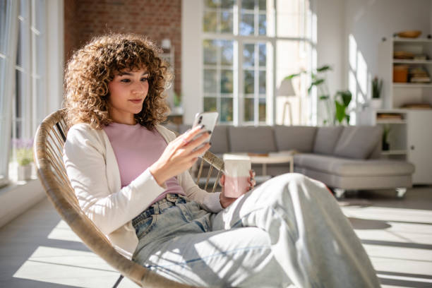 istock Young woman relaxing at home while using smartphone and drinking coffee 2189539224