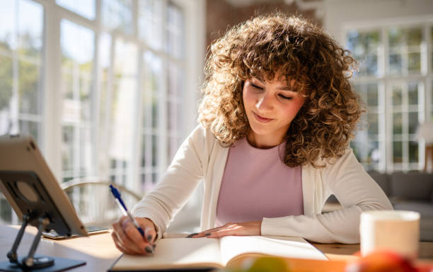 istock Woman writing in a bright room on a sunny day 2189539328