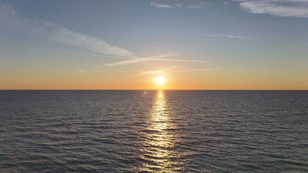 Beautiful sunset over a calm ocean with a clear sky reflecting golden hues on the water.