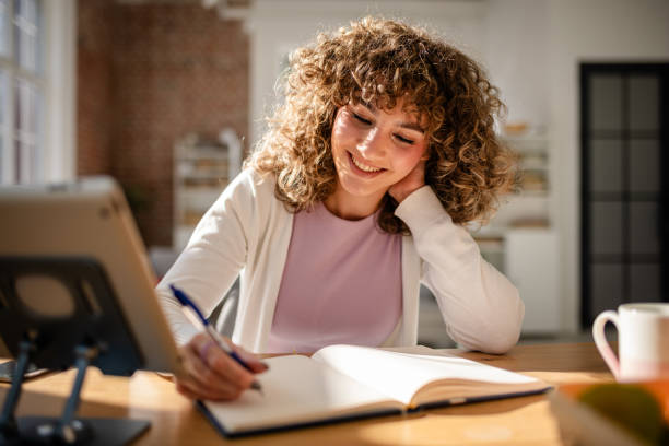 istock Young woman smiling while taking notes at her desk during the day 2189540263