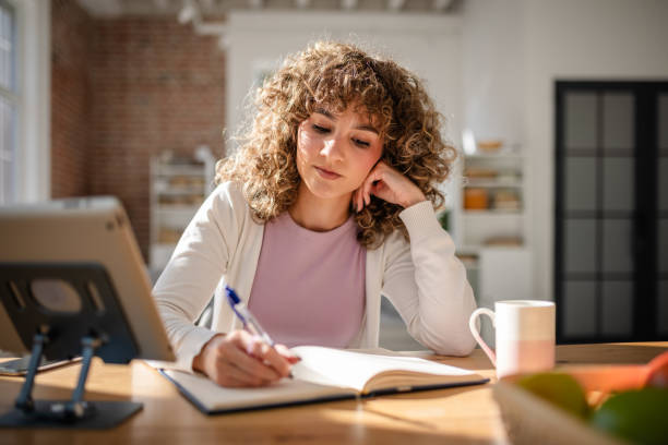 istock Young Woman Writing Notes at a Desk in a Sunlit Home 2189540295