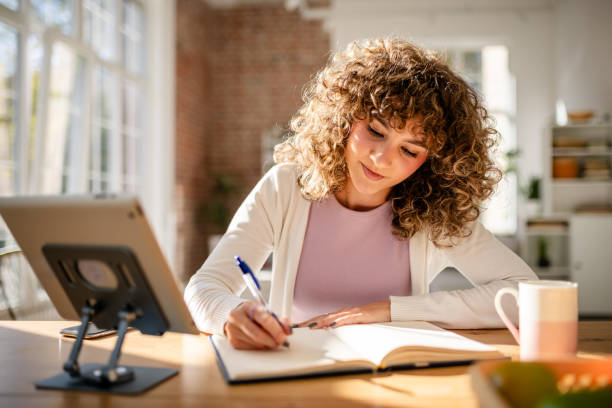 istock Young woman writing notes in a bright and cozy home office 2189540533