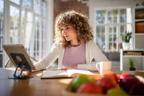 istock Woman working with a tablet and notebook in a bright modern home 2189540632