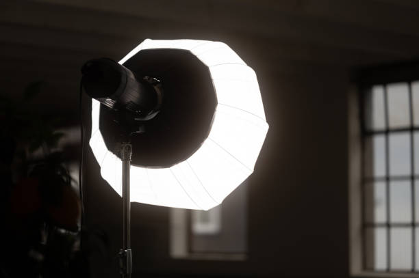 Bright studio flash with a softbox modifier illuminating a dark room, creating a dramatic atmosphere for photography or videography