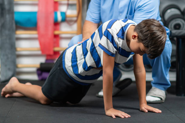istock Boy in physical therapy working on core exercises with a physical therapist, aimed at enhancing core strength, stability, and balance during rehabilitation 2189541960