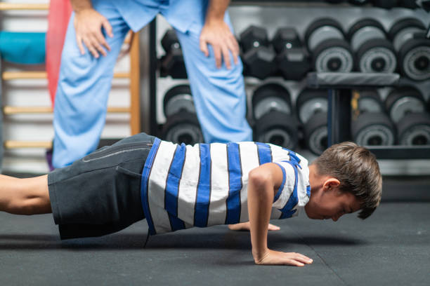 istock Young boy working with a physical therapist during a rehabilitation session, performing exercises to improve strength, balance, and motor skills in a supportive environment 2189542030