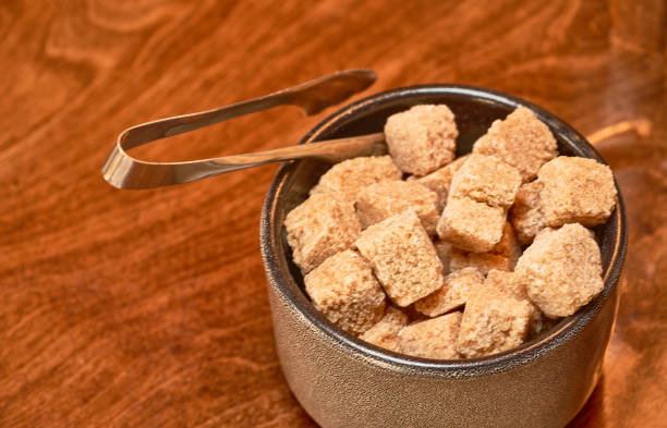 Brown cane sugar in a cup on a wooden table. Selective focus.