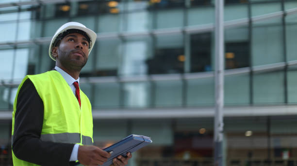 istock Architect inspecting building using digital tablet and wearing safety vest and helmet 2189547353