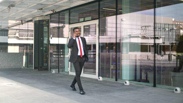 istock Businessman walking and talking on phone outside office building 2189547361
