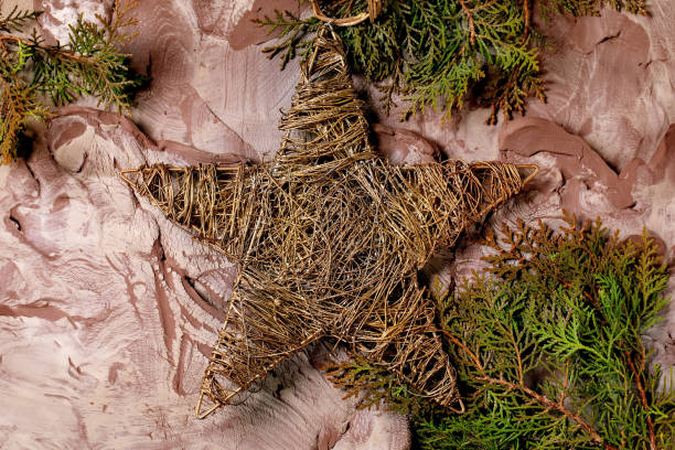 Christmas New Year background in the 2025 color of the year, Mocha Mousse. Christmas decorations big golden star and green branches on nerikomi-style raw clay mixture background. Top view.
