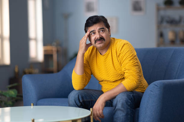 istock Man sitting alone at home looking sad and distraught stock photo 2189549062
