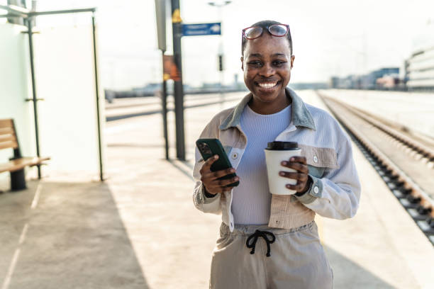 istock A beautiful woman is using a mobile phone at a train station while waiting to get into a train car. 2189549527