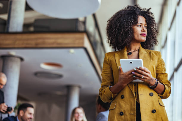 Confident Woman in Modern Office Holding a Tablet During Work