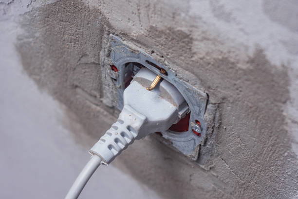 Close-Up of a power plug connected to an electrical socket during renovation. Electrical socket with a plug connected on a dusty wall, representing renovation work