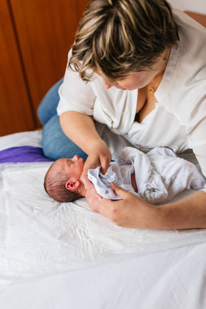 istock Mother changing her newborn baby's clothes on bed 2189551193