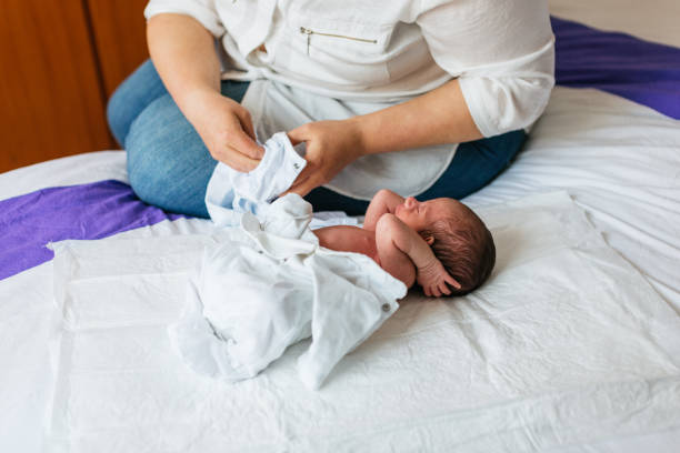 istock Mother dressing her newborn baby son on a bed 2189552579