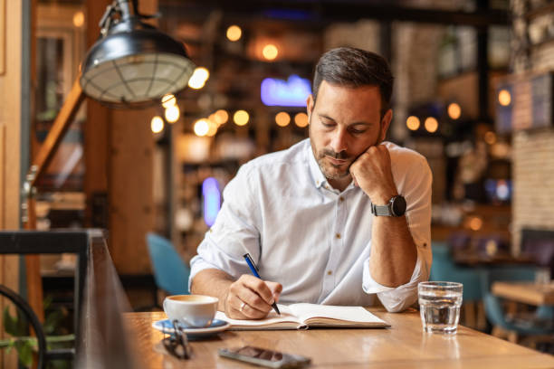 istock Businessman in a cafe - Sipping coffee and writing ideas 2189557013