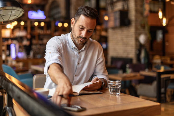 istock Businessman in a cafe - Drinking coffee, talking on the phone, and writing notes 2189557031