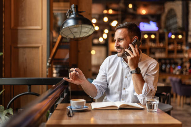 istock Businessman in a cafe - Drinking coffee, talking on the phone, and writing notes 2189557057