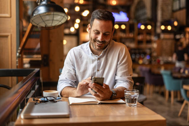 istock Businessman in a cafe - Drinking coffee, talking on the phone, and writing notes 2189557067