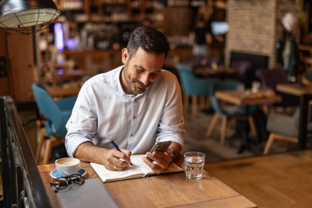 istock Businessman in a cafe - Sipping coffee and writing ideas 2189557075