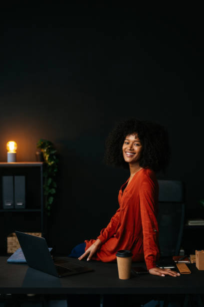 istock Young manager sitting on her desk smiling at the camera in her office 2189558093