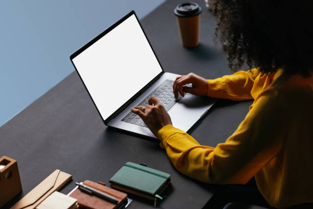 Young woman working on laptop with blank screen in modern office