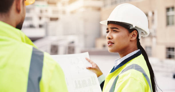 istock Roof, floor plan and people with construction for inspection, urban development or planning in city. Man, woman or contractors with paperwork or blueprint for building layout or architecture in town 2189559179
