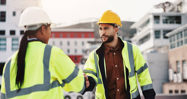 istock Architecture, man and woman on building shaking hands for inspection, agreement or introduction in city. Civil engineering, contractor and technician on roof with handshake, deal or teamwork on site 2189559230
