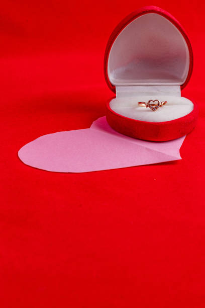 istock Diamond wedding ring in a box on a paper pink heart on a red background 2189559809