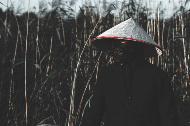 istock A mysterious samurai with a black mask and a conical hat stands in a bamboo forest, creating a mysterious and mesmerizing scene. The handsome samurai warrior conveys strength and power. 2189563445