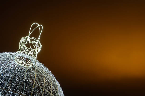 Glowing Christmas tree ball on an orange sky background. Christmas background. Minimalism. High quality photo