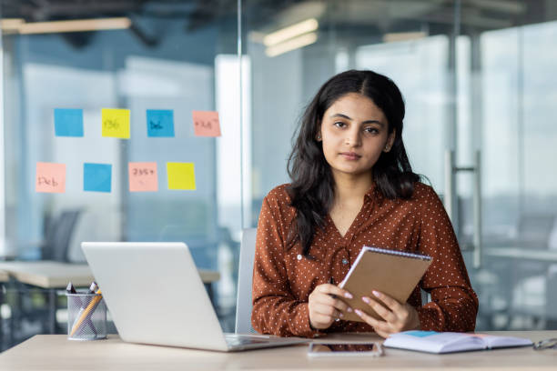 istock Businesswoman analyzing tasks with a notepad in a modern office environment 2189567170