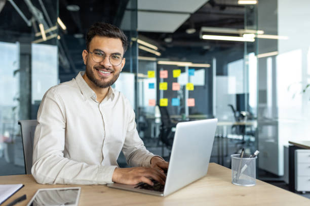 Confident young businessman working on a laptop in a modern office setting