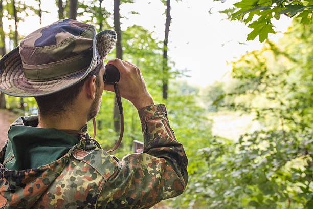 istock Soldier wearing camouflage uniform observing with binoculars in forest 2189567804