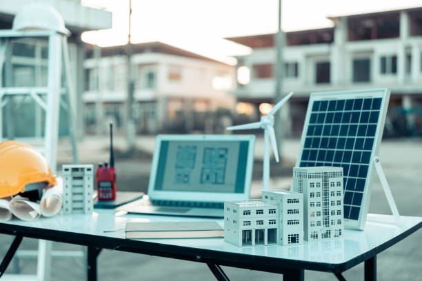 istock Laptop with display of tools, house plans and blueprints on table at architectural construction site, model of home ownership in construction plans, laptop in background 2189569470