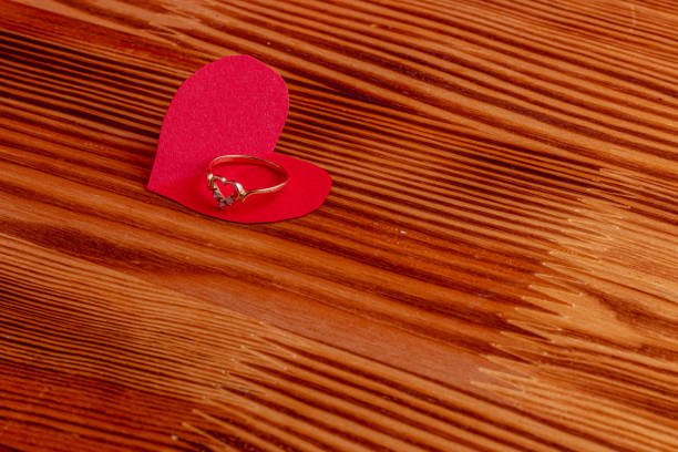 Wedding ring on a paper heart on a wooden board High quality photo.