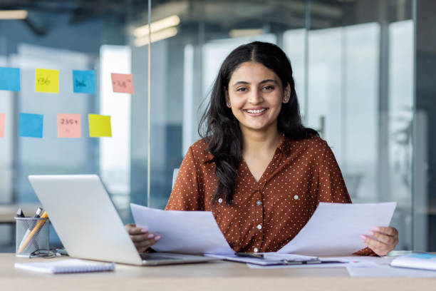 istock Smiling businesswoman holding documents in a modern office environment 2189569818