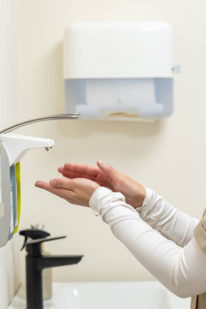 istock Nurse disinfecting hands with automatic dispenser in hospital bathroom 2189570421
