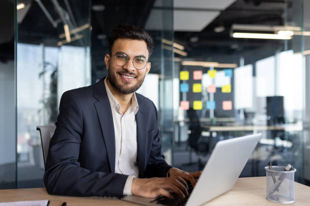 istock Smiling businessman working on a laptop in a modern office space 2189570833