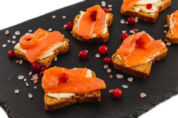 istock Toasts with butter salmon and cranberries on a stone board on a white background 2189573978