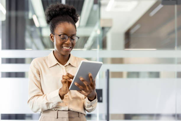 istock Smiling businesswoman using tablet in modern office environment, focused on digital work, innovation, and technology integration. Professional attire emphasizes corporate culture and efficiency. 2189580631