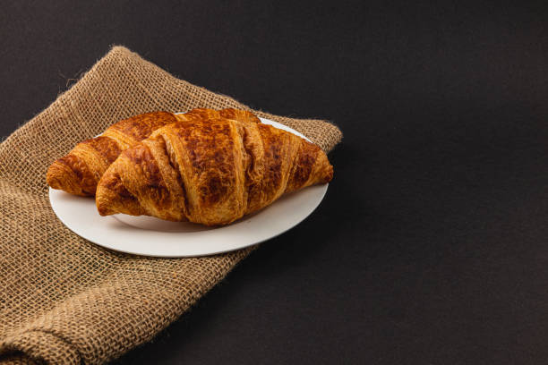 Two golden croissants on a white plate, perfect for a delightful breakfast