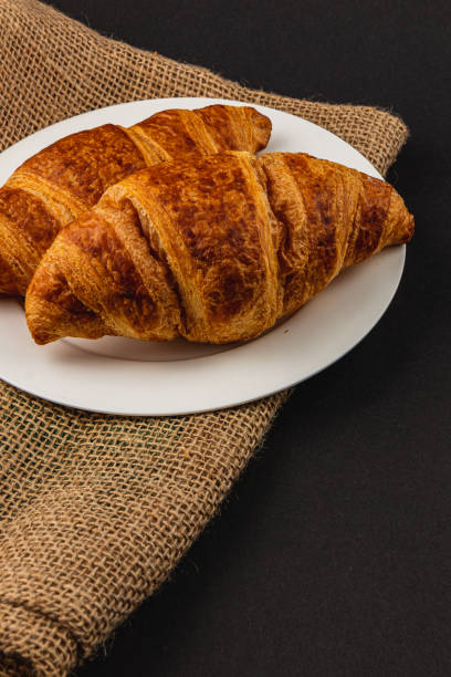 Two golden croissants on a white plate, perfect for a delightful breakfast