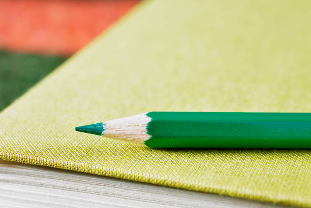 Pointed green wooden pencil on green hardcover book ,place of work o leisure time