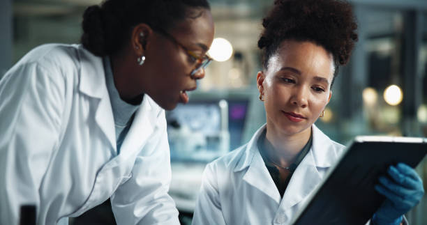 istock Science, women or reading in lab with tablet, feedback and scientific research at night. Scientist team, tech or brainstorming in facility for deadline advice, pharmaceutical development or app study 2189583486