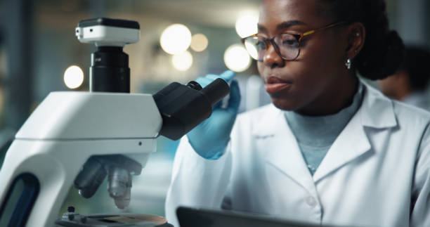 istock Black woman, scientist and microscope for disease research and medical study with pharma investigation. Virus, biotechnology and vaccine test for health science with working healthcare professional 2189583509