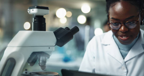 istock Black woman, microscope and research with laptop for science experiment, test analysis or biotechnology. Computer, happy scientist and microbiology for medical development, healthcare and pharma lab 2189583516