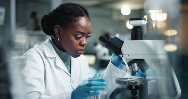 istock Black woman, scientist and microscope for lab research and medical study with pharma investigation. Virus, biotechnology and vaccine testing for health science with working healthcare professional 2189583542