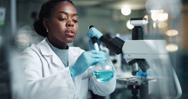 istock Scientist, black woman and beaker with microscope for biochemistry, experiment and pathology research. Chemical, analysis and pipette for liquid inspection, pharmaceutical development and DNA study 2189583551